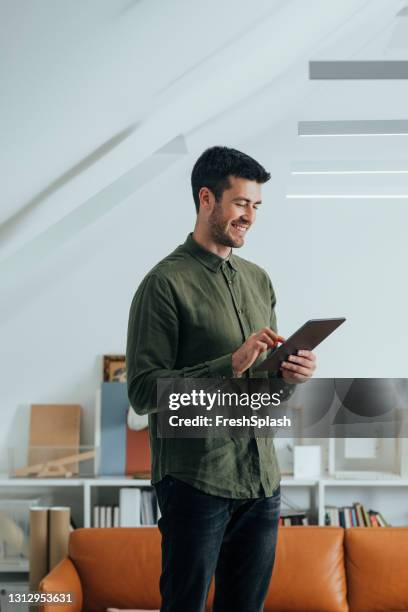 uomo sorridente con una camicia verde usando un tablet digitale in ufficio - digital tablet foto e immagini stock