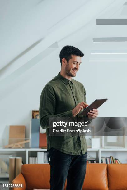 homem sorridente de camisa verde usando um tablet digital no escritório - mesa digital - fotografias e filmes do acervo