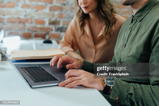 anonymer geschäftsmann in einem grünen hemd, der auf einem laptop-computer arbeitet, während er hilfe von seinem mitarbeiter, einem close up - modern business people close up stock-fotos und bilder