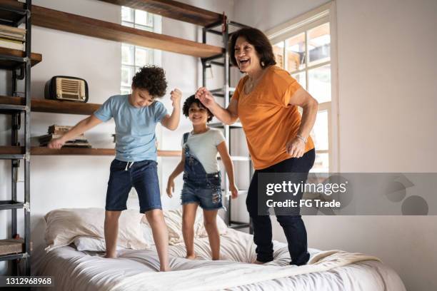 grand-mère jouant avec le petit-enfant �à la maison - sauter sur le lit photos et images de collection