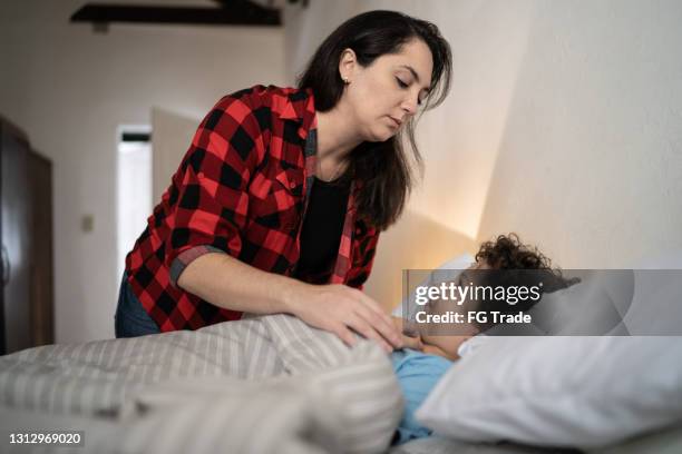 moeder die zoon aan slaap thuis zet - kids sleep in bed stockfoto's en -beelden