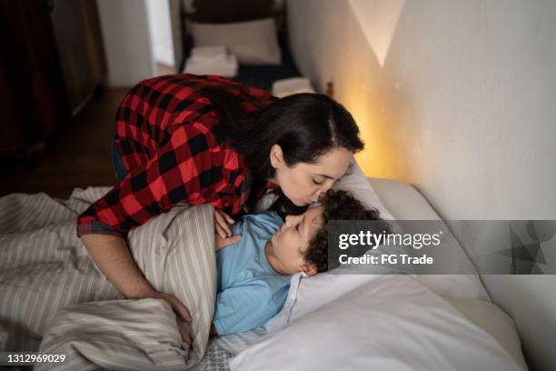 mother putting son to sleep at home - bedtime stock pictures, royalty-free photos & images