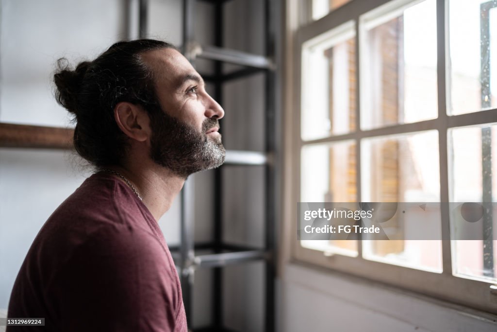 Man looking through the window at home