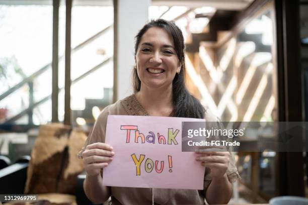 frau hält papier mit "danke" zu hause geschrieben - thank you englischer satz stock-fotos und bilder