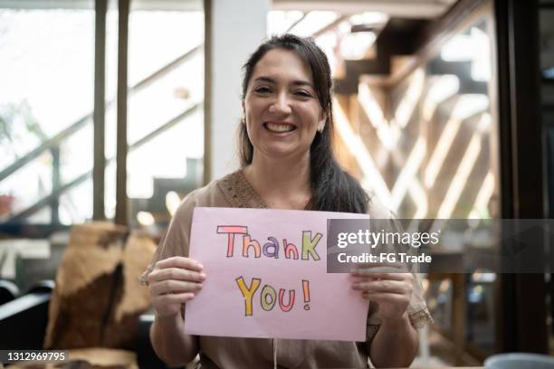 woman holding paper with 'thank you' written at home - thank you smile stock pictures, royalty-free photos & images