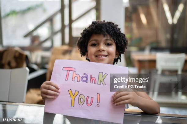 girl holding paper with 'thank you' written at home - congratulating child stock pictures, royalty-free photos & images