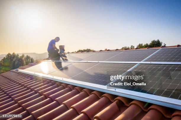 ouvrier professionnel installant des panneaux solaires sur le toit d’une maison. - effet miroir homme photos et images de collection