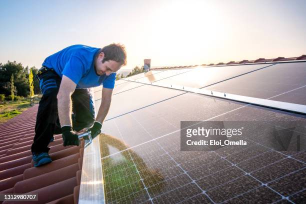 professional worker installing solar panels on the roof of a house. - professional drag stock pictures, royalty-free photos & images