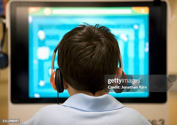 school boy in a computer lab. - boy headphones imagens e fotografias de stock