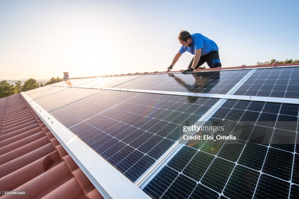 Professional worker installing solar panels on the roof of a house.