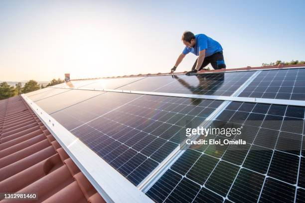 professionell arbetare som installerar solpaneler på taket av ett hus. - implementation bildbanksfoton och bilder