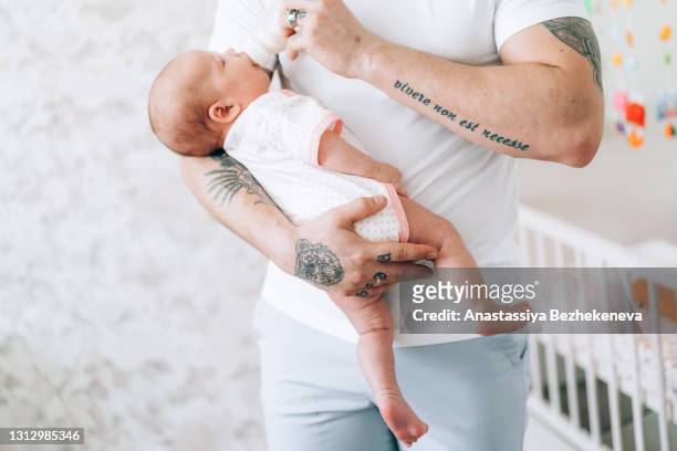 young father is holding his newborn baby in his arms and feeding from bottle. love and care for children. adoption of children. the child grows up without a mother - dia bildbanksfoton och bilder
