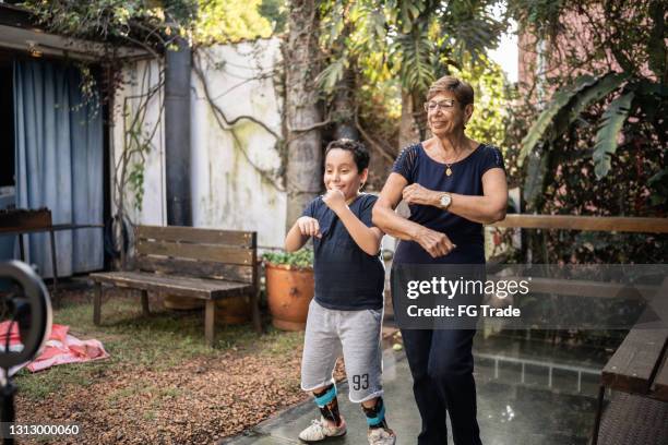 niño bailando con abuela y filmándolo en casa - latina legs fotografías e imágenes de stock