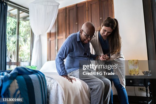 Aide à domicile aidant un homme aîné restant vers le haut à la maison Aide à domicile aidant un homme aîné restant vers le haut à la maison