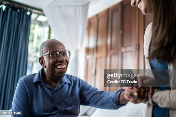 hemtjänsttagare pratar med patient hemma - african american man helping elderly bildbanksfoton och bilder