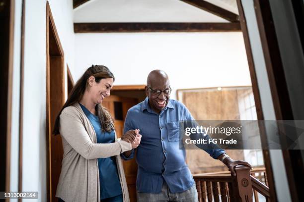 de verzorger die van het huis hogere mens helpt die thuis loopt - geriatrie stockfoto's en -beelden