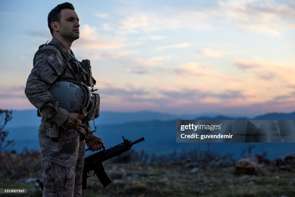 Army Soldier standing against sunset sky in battlafield