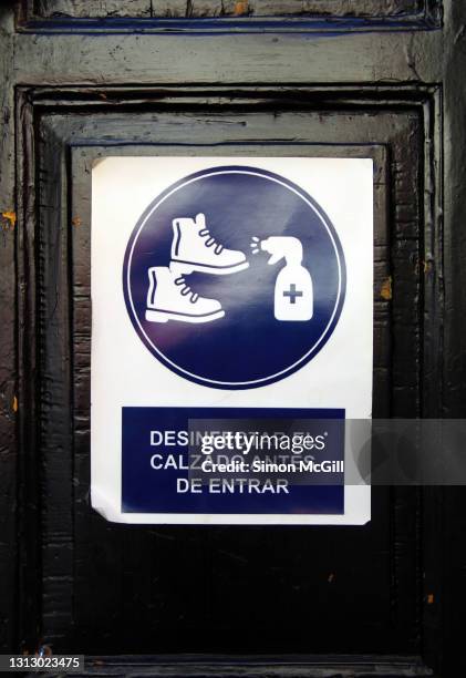 spanish-language sign on a front door stating 'desinfectar el calzado antes de entrar' [disinfect footwear before entering] - entrar stockfoto's en -beelden