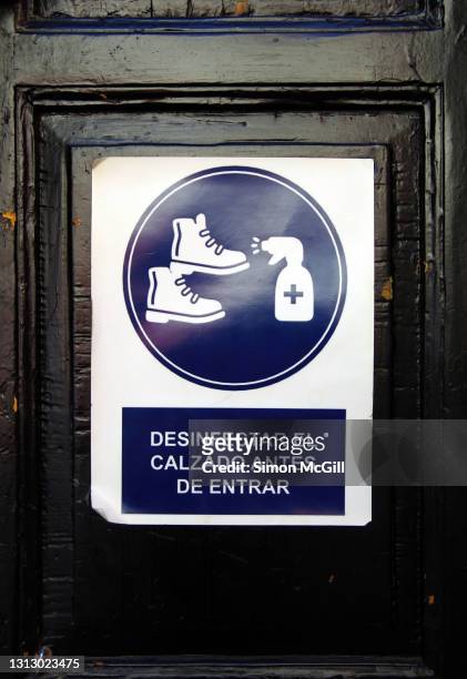 spanish-language sign on a front door stating 'desinfectar el calzado antes de entrar' [disinfect footwear before entering] - calzado stock pictures, royalty-free photos & images