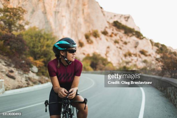 portrait of cyclist woman on road triathlon bike with amazing mountain view on highway. - women road cycling stock pictures, royalty-free photos & images