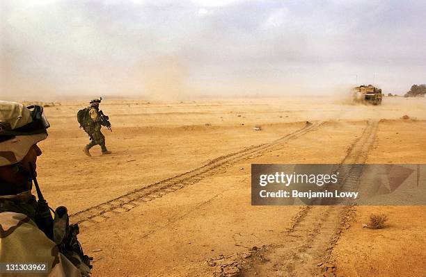 Soldiers with the 1st Brigade of the 101st Airborne Division run behind tanks during an assualt on a complex used by Iraqi soldiers launching mortars...