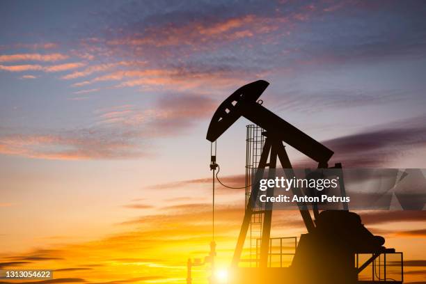 oil pump on a sunset background. world oil industry - gasolina stock-fotos und bilder