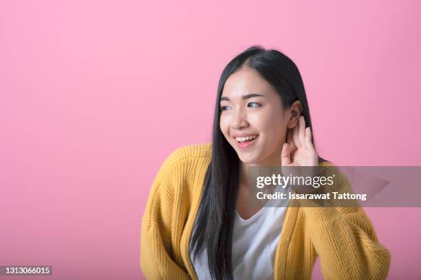 young pretty blonde woman looking serious and curious, listening, trying to hear a secret conversation or gossip, eavesdropping against pink wall - tendre l'oreille photos et images de collection