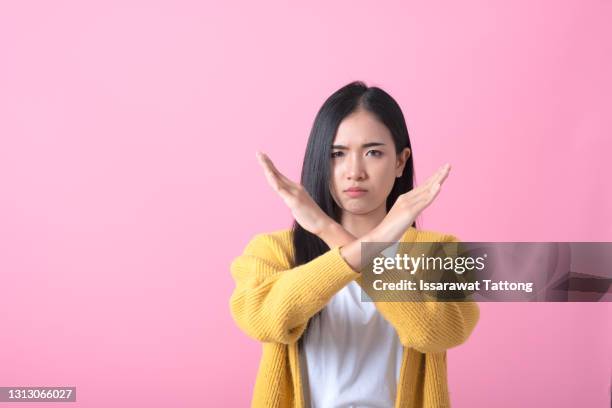 definitely no, prohibited access! portrait of girl crossing hands, showing x sign, stop gesture, warning of end finish, forbidden way. indoor studio shot isolated on pink background - verweigern stock-fotos und bilder