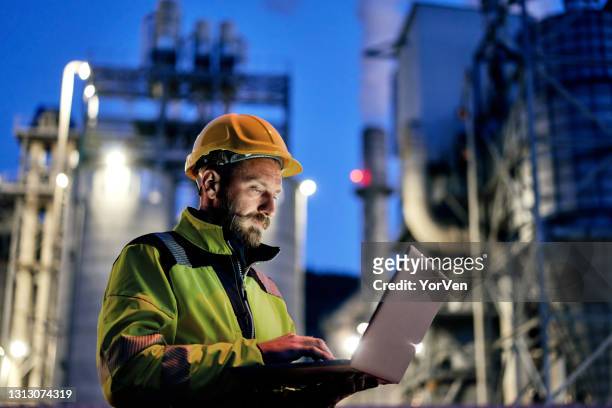 male engineer using laptop during night shift. - headwear photos stock pictures, royalty-free photos & images