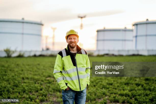 verticale de l’ingénieur de sourire devant la raffinerie de pétrole - centrale nucléaire photos et images de collection