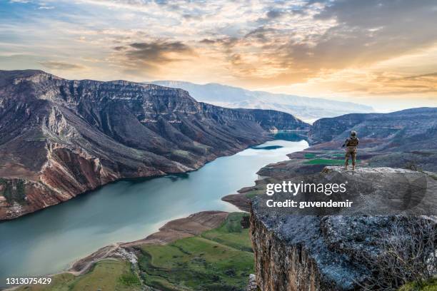 male soldier standing against sunset on the top of cliff - remote guarding stock pictures, royalty-free photos & images