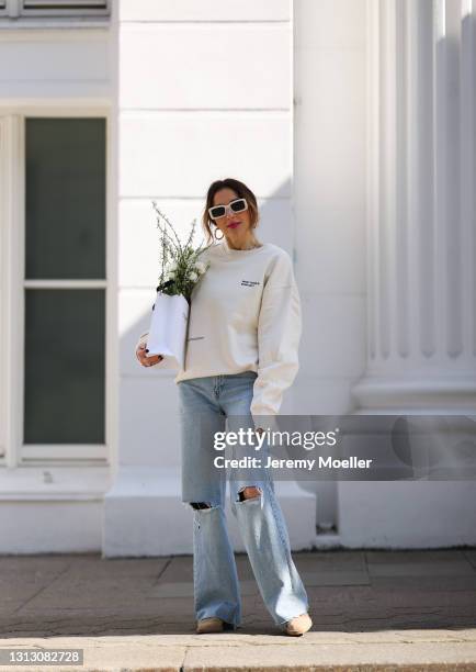 Elise Soho wearing beige Closed shoes, Zara shades and blue destroyed jeans, Celine paper bag and beige Hey Soho sweater on April 16, 2021 in...