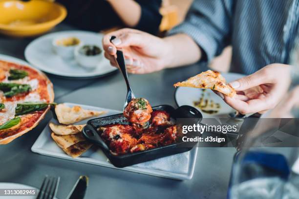 close up of young asian woman enjoying freshly served meatballs and bolognese while having lunch in an outdoor restaurant. italian cuisine and culture. eating out lifestyle - vleesgerecht stockfoto's en -beelden