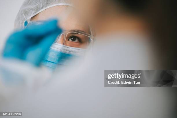 asiatisk kinesisk kvinnlig läkare med ppe tar nasala svabbprov från patienten coronavirus test. sjukvårdspersonal i skyddssvit tar en svabb för coronavirustest, potentiellt smittad kvinna - bioteknologi bildbanksfoton och bilder