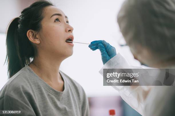 asian chinese female doctor with ppe taking mouth swab from patient coronavirus test. medical worker in protective suite taking a swab for corona virus test, potentially infected woman - cotton bud stock pictures, royalty-free photos & images