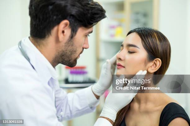 doctor examining and explaining asian women patient's face for improvement of her skin at a beauty clinic. skin care clinic business. - dermatologia foto e immagini stock