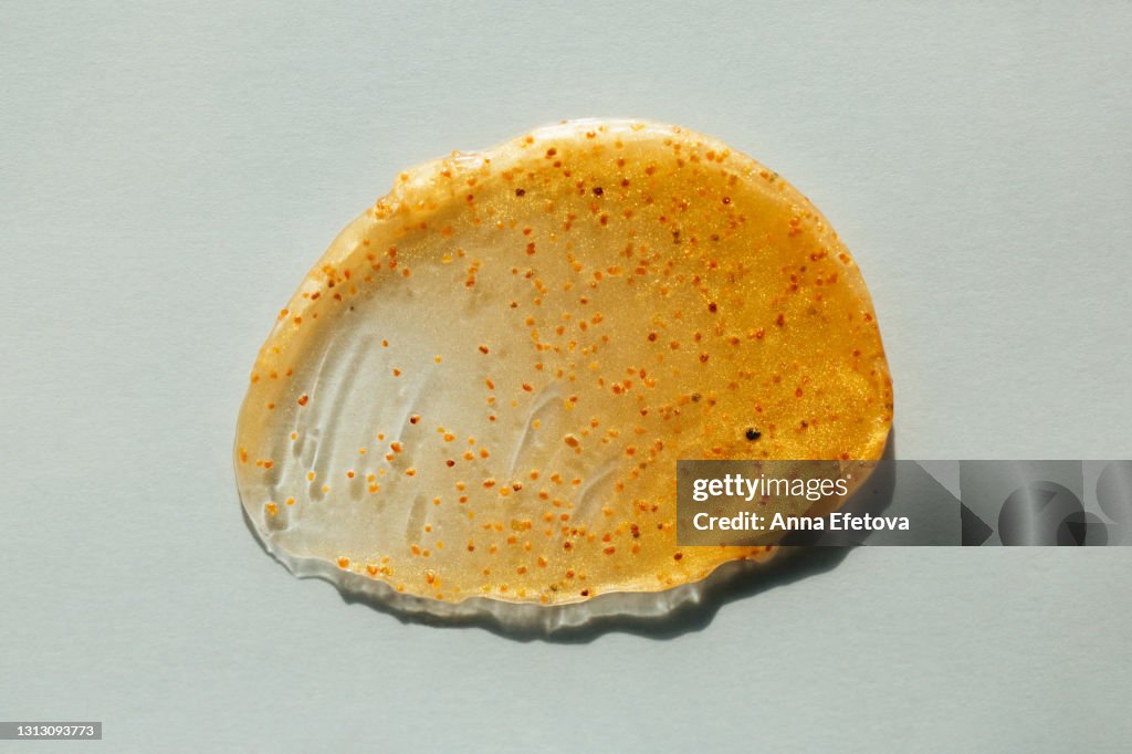 Smear of orange sorbet with seeds on light blue background. Flat lay style and close-up