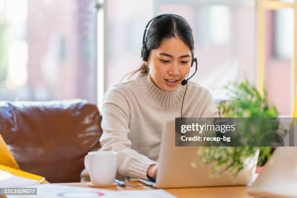 young woman using laptop in living room at home - headset stock pictures, royalty-free photos & images