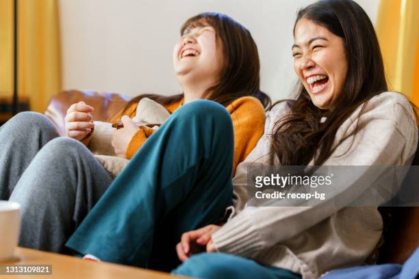 två systrar tittar på bärbar dator medan de äter popcorn - asian cinema bildbanksfoton och bilder