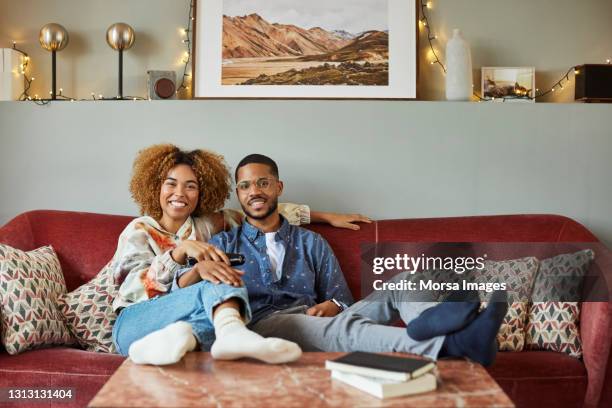 smiling woman with boyfriend watching tv at home - casal-de-verdade imagens e fotografias de stock