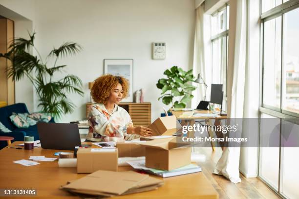 freelancer analyzing packaging in living room - freelance work from home stock pictures, royalty-free photos & images