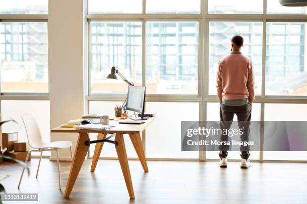 thoughtful businessman looking through window - behind window stock-fotos und bilder