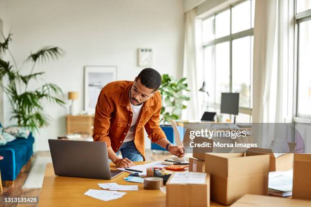 businessman analyzing documents in home office - klein bedrijf stockfoto's en -beelden