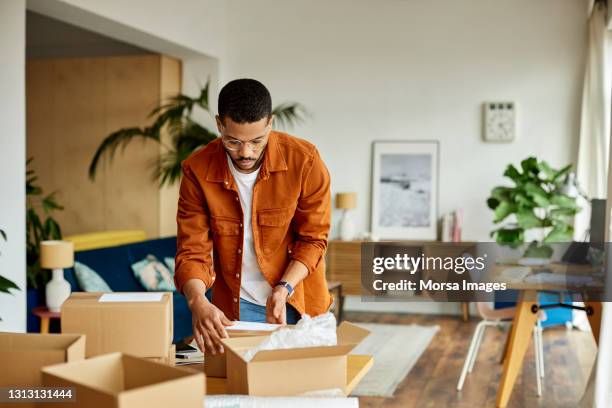 young businessman packing cardboard box at table - verpakking stockfoto's en -beelden