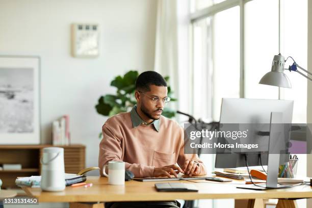 freelancer using computer at home office - personas trabajando fotografías e imágenes de stock