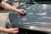 Installation of a protective paint and varnish transparent film on the car. PPF polyurethane film to protect the car paint from stones and scratches.
