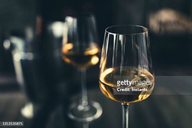 close-up of two glasses of white wine and, in background, a bottle in an ice bucket. - canada wine stock pictures, royalty-free photos & images