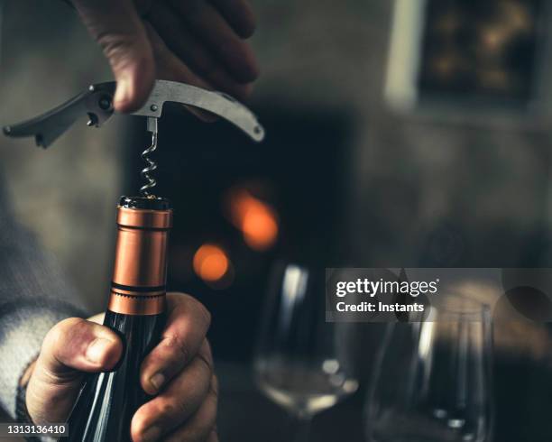 primer plano de un hombre, con un sacacorchos en la mano, abriendo una botella de vino blanco. - wine bottle fotografías e imágenes de stock