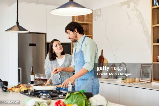 woman looking at man preparing meal in kitchen - kitchen fridge imagens e fotografias de stock