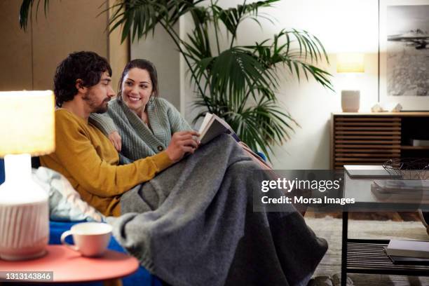 couple spending time together in living room - mid adult couple stock pictures, royalty-free photos & images